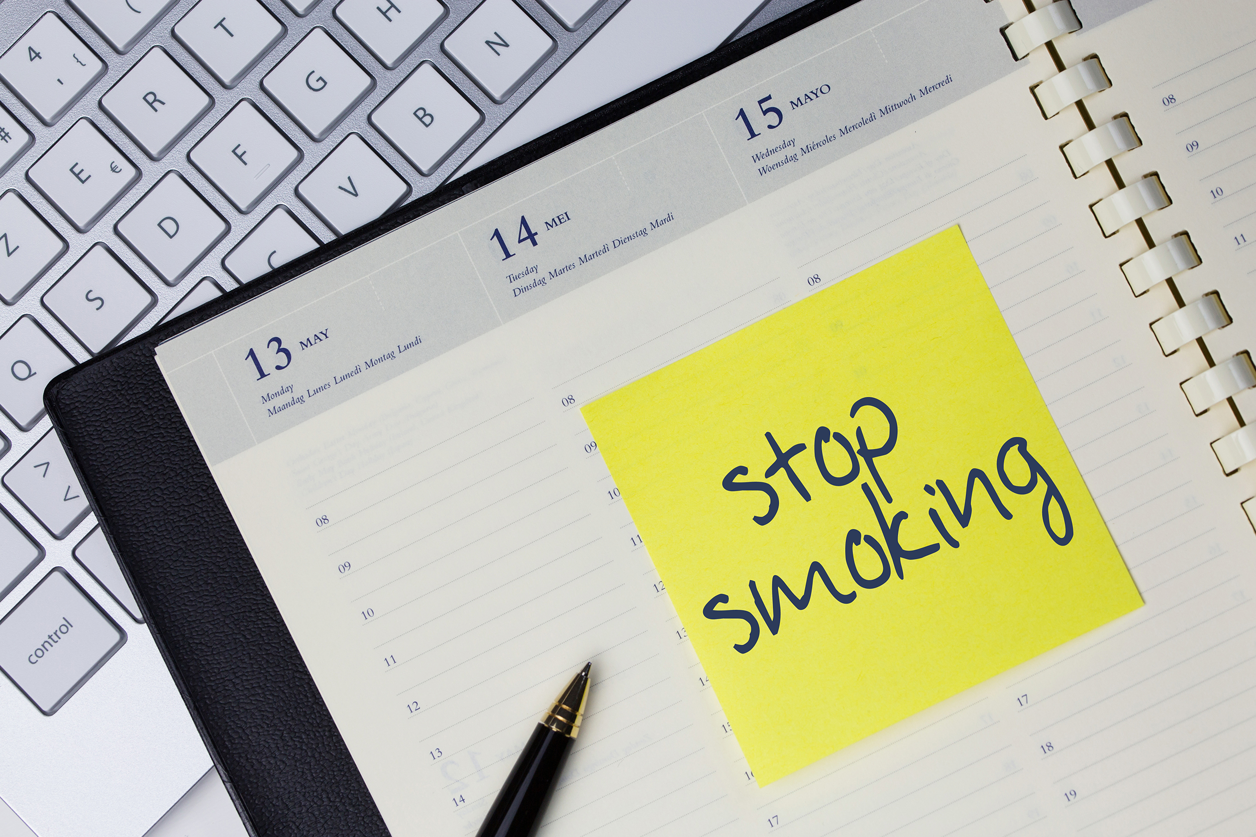 Werkplek met laptop en agenda waarin staat: stop smoking (stoppen met roken)