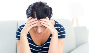 Vrouw met haar handen op haar hoofd door de stress.